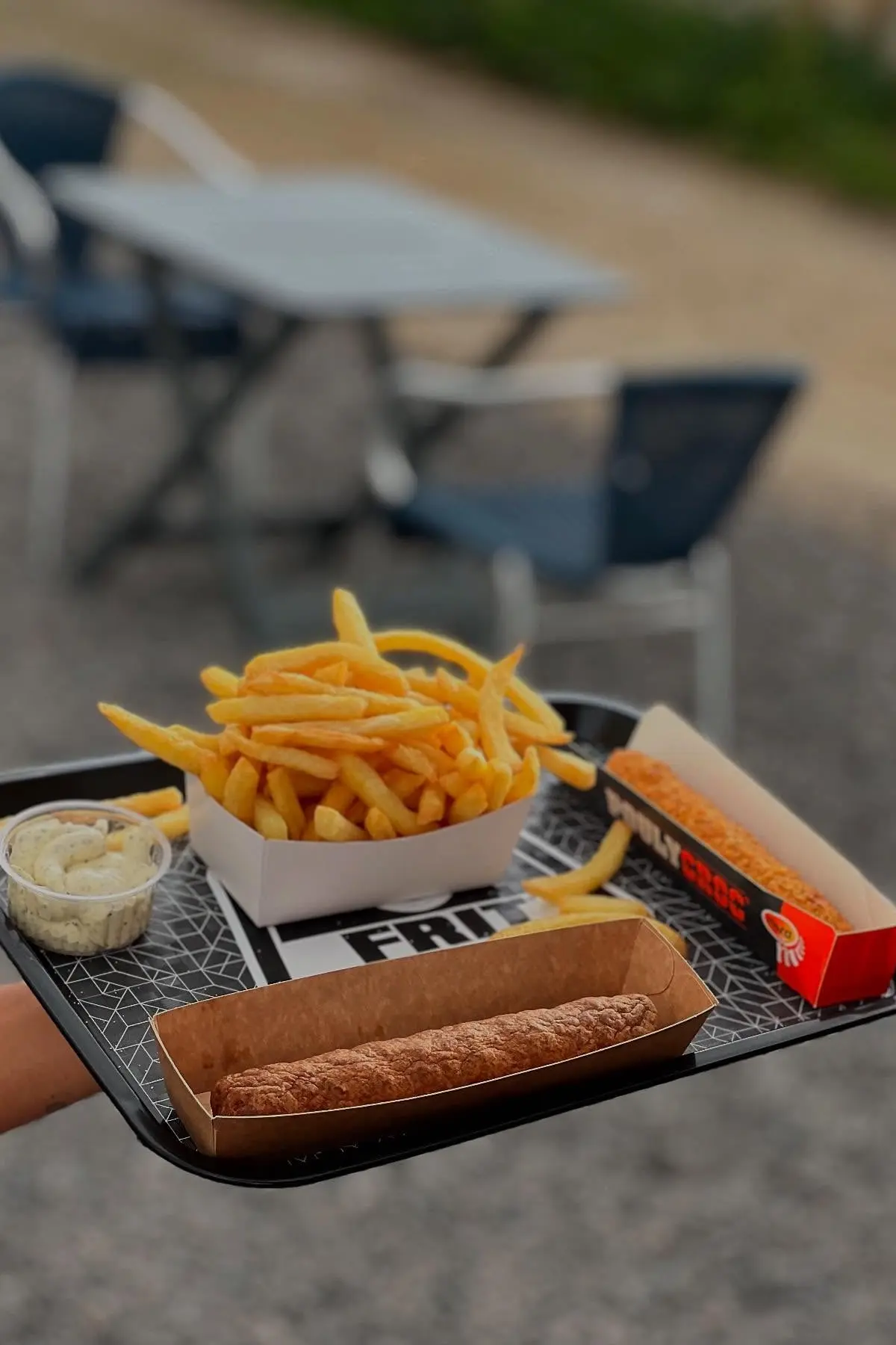 Frites belges croustillantes servies avec une fricadelle à la Friterie de l'Alliance